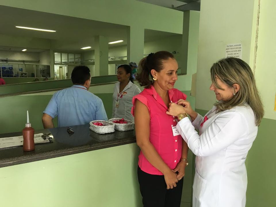 Funcionária recebendo o laço rosa, símbolo da campanha Outubro Rosa. Foto: Daianni Parreira