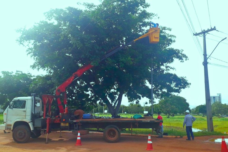 Foto de profissionais trabalhando na troca de lâmpadas perto de um caminhão