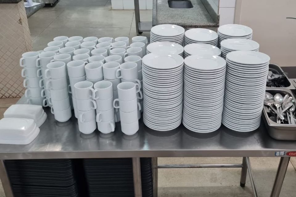 Foto de um conjunto de pires, xícaras e talheres de café da manhã, sob uma bancada