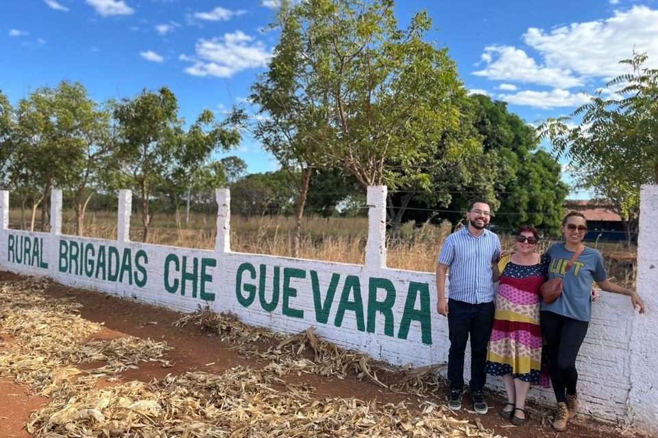 Um homem e duas mulheres em frente ao muro da escola 