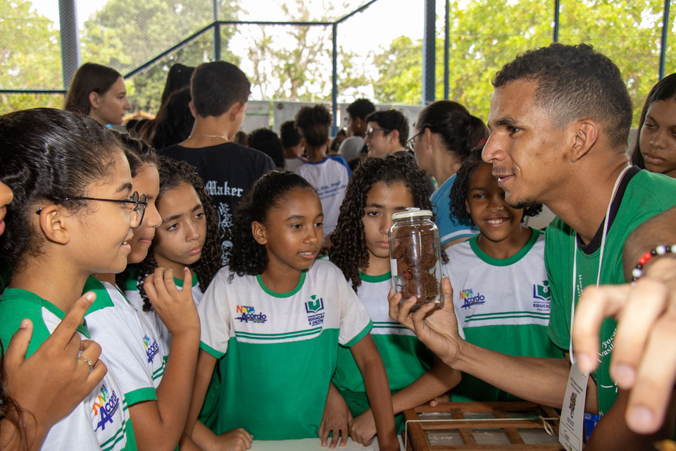 homem mostra um pote de planta para grupo de crianças