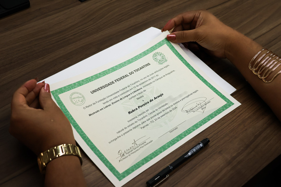 foto mostra mãos femininas segurando um diploma com o nome de Rubra Pereira de Araújo