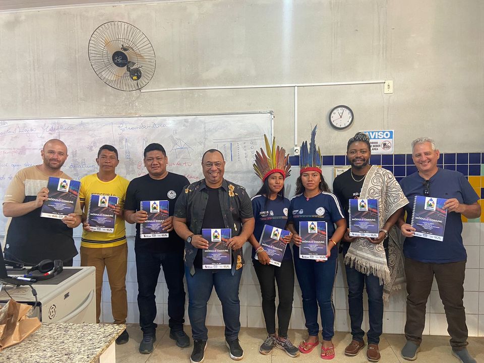 Alunos indígenas pousados para a foto segurando as apostilas