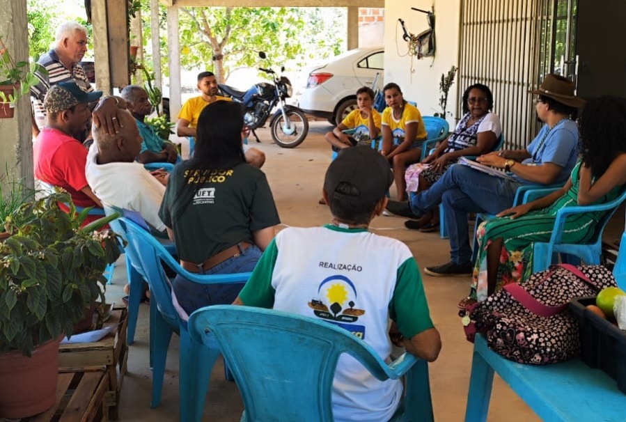 Grupo de pessoas sentadas em círculo na casa da casa de uma líder do Ráizes do Quilombo