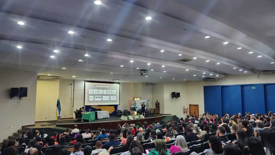 foto de auditório cheio com projeção de imagens em um telão