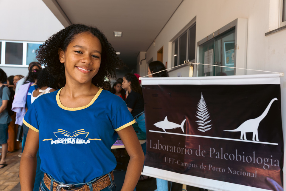 menina com uniforme escolar sorri pra foto 
