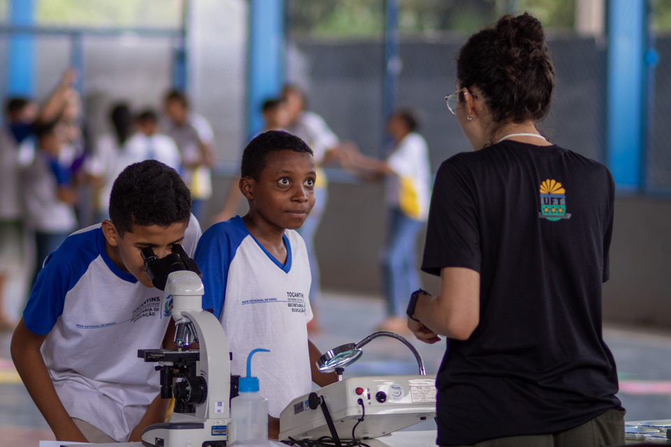 estudantes olham por um microscópio