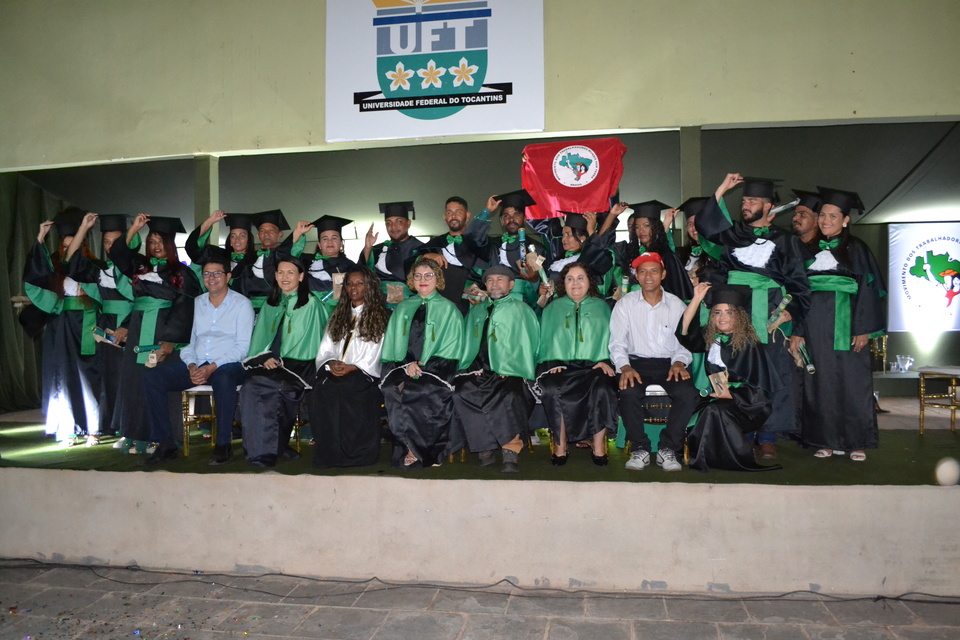 20 pessoas com roupas de formatura segurando o chapéu de formando