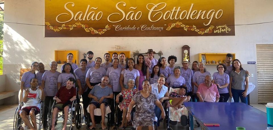 Participantes do programa de extensão reunidas para tirar foto junto com os idosos do Abrigo João XXIII