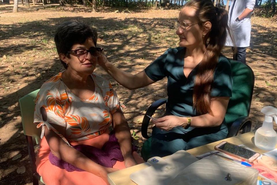 Foto de uma mulher sendo atendida por profissional em momento de prática integrativa ao ar livre