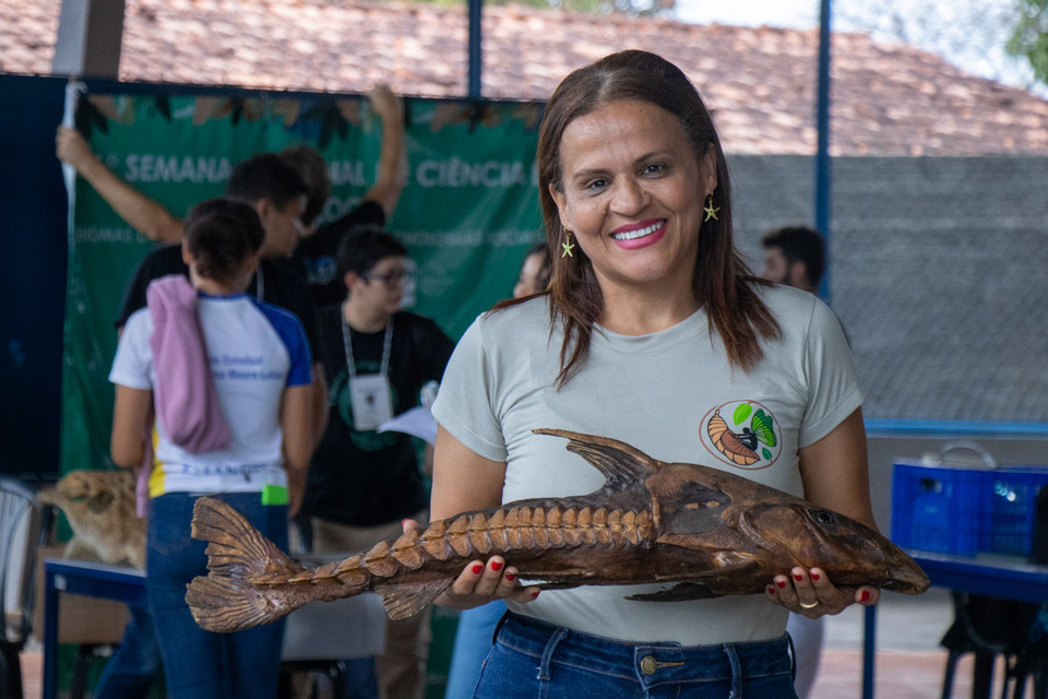 professora segura um fóssil de peixe