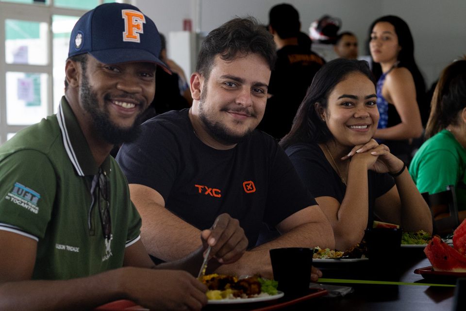 Três estudantes sentados e almoçando no restaurante universitário da UFT